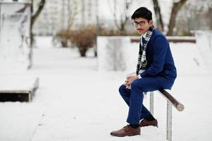 stijlvolle Indiase student man in pak, bril en sjaal poseerde op winterdag buiten. foto