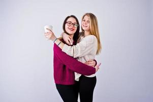 portret van twee vriendinnen in kersenjurken poseren met een kopje koffie in de studio. foto