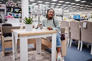 afrikaanse vrouw die het juiste meubilair kiest voor haar appartement in een moderne woninginrichtingswinkel. foto