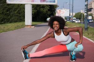 portret van sportieve jonge Afro-Amerikaanse vrouw die zich buiten uitstrekt foto