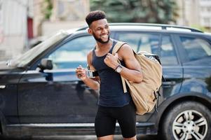 Afro-Amerikaanse mannelijke atleet sport man met rugzak tegen zijn zwarte SUV-auto voor de training. foto