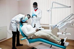 Afro-Amerikaanse man patiënt in tandartsstoel. tandartspraktijk en dokterspraktijkconcept. professionele tandarts die zijn patiënt helpt bij medische tandheelkunde. injectie verdoving. foto