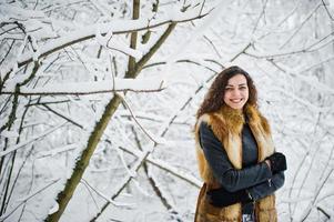 elegantie krullend meisje in bontjas in besneeuwde forest park in de winter. foto