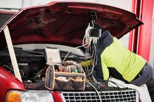 automonteur stelt Amerikaanse SUV-auto in voor diagnostiek en configuratie in werkplaatstankstation.. foto