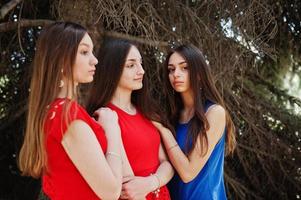 drie tieners meisje in blauwe en rode jurken poseerde buiten. foto