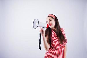 portret van een jonge mooie vrouw in rode jurk praten in megafoon. foto