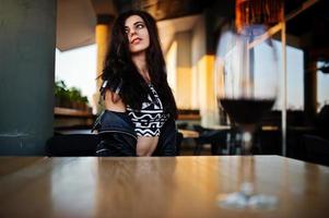 jonge krullende vrouw genieten van haar wijn in een bar. foto
