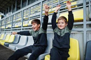 twee broers steunen hun favoriete team, zittend op het sportpodium in het stadion. foto