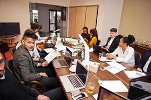 multiraciale business team adressering vergadering rond boardroom tafel. foto