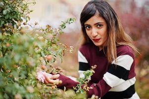 portret van jonge mooie Indiase of Zuid-Aziatische tienermeisje in jurk op bloementuin. foto