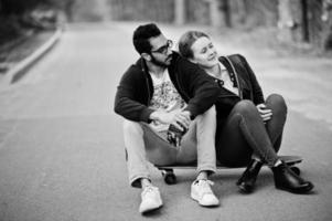 cool multiraciaal paar zittend op longboard op weg. foto