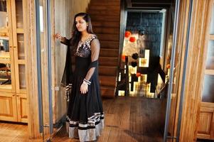 vrij indiase meisje in zwarte saree jurk gesteld bij restaurant. foto
