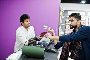 indiase man klant koper betaalt voor zijn nieuwe smartphone voor verkoper met creditcard bij mobiele telefoon winkel. Zuid-Aziatische volkeren en technologieën concept. gsm winkel. foto