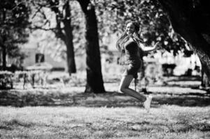 schattig en slank Afrikaans Amerikaans meisje in rode jurk met dreadlocks springen buiten in het voorjaarspark. stijlvol zwart model. foto