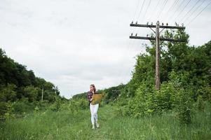 portret van een mooi blond meisje in tartan shirt wandelen met een kaart op het platteland. foto