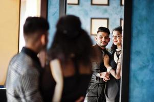 mooi indisch verliefd stel, draag bij saree en elegant pak, poseerde op restaurant en kijkend naar spiegel. foto