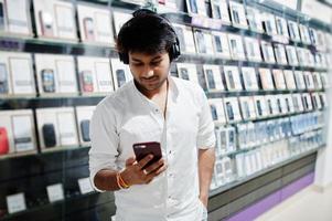 indiase man klant koper bij mobiele telefoon winkel luister muziek van draadloze oortelefoons verbinding maken met zijn smartphone. Zuid-Aziatische volkeren en technologieën concept. gsm winkel. foto