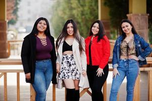 groep van vier gelukkige en mooie latino-meisjes uit ecuador poseerden op straat. foto