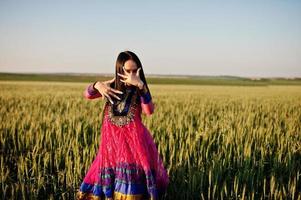 teder indisch meisje in saree, met paarse lippen make-up geposeerd op het veld bij zonsondergang. modieus Indiaas model. foto