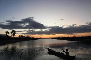 visser op zijn boot bij zonsondergang. vissersboot bij zonsondergang foto