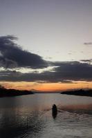 visser op zijn boot bij zonsondergang. vissersboot bij zonsondergang foto