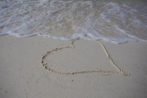 harten getekend op het zand van een strand foto