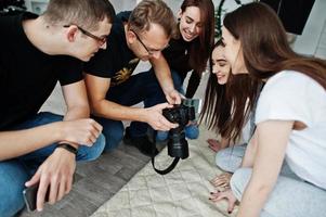 het team van fotografen die foto's op het scherm van de camera tonen voor tweelingmodellen, meisjes in de studio. professionele fotograaf op het werk. foto