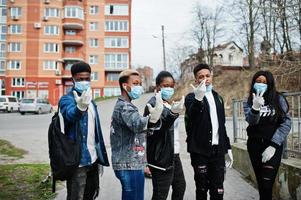 groep afrikaanse tieners vrienden tegen lege straat met gebouw met medische maskers beschermen tegen infecties en ziekten coronavirus virus quarantaine. foto