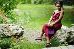 portret van een mooie natuurlijke jonge afrikaanse vrouw met afrohaar. zwart model in rode zijden jurk. foto