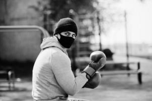 portret sport arabische bokser man in zwart medisch gezichtsmasker boksen buiten tijdens coronavirus quarantaine. foto
