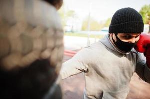 portret sport arabische bokser man in zwart medisch gezichtsmasker boksen buiten tijdens coronavirus quarantaine. foto