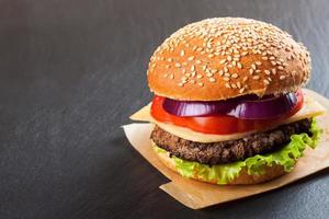 zelfgemaakte cheeseburger op zwarte leisteen oppervlak. foto