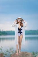portret van mooie aziatische sexy vrouw die 's avonds bikini aan de rotskant van de zee draagt, levensstijl van moderne vrouwen, mensen uit thailand foto