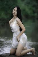 portret van sexy Aziatische vrouw bij de waterval, fris voelen aan de rivier, Thaise vrouw ontspannen op het platteland foto