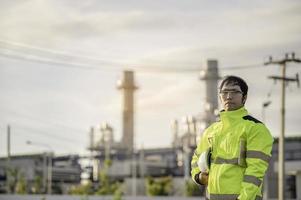 aziatische man petrochemisch ingenieur aan het werk bij de fabriek van de olie- en gasraffinaderij, de mensenarbeider man ingenieur werkcontrole bij de productie van de energiecentrale foto