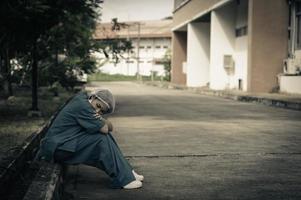 vermoeide depressieve vrouwelijke Aziatische scrubverpleegster draagt gezichtsmasker blauw uniform zit op de ziekenhuisvloer, jonge vrouwelijke arts gestrest van hard werken foto