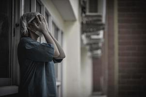 vermoeide depressieve vrouwelijke Aziatische scrubverpleegster draagt gezichtsmasker blauw uniform zit op de ziekenhuisvloer, jonge vrouwelijke arts gestrest van hard werken foto