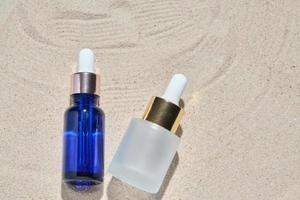 gezichtsserum van glazen fles met een pipet op een natuurlijke achtergrond met zand. etherische olie voor het hydrateren van de lichaamshuid. mockup van beauty fashion cosmetische fles dropper product met huidverzorging concept. foto