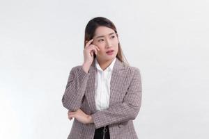 Aziatische zakenvrouw in formeel pak denkt iets op een witte achtergrond. foto