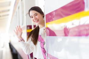 aziatische mooie vrouw zegt vaarwel tegen haar familie vanwege het werken in de stad met de trein of ze komt aan en zegt welkom thuis op het station. foto