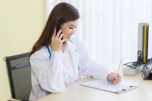 Aziatische vrouwelijke artsen bieden telefonische counseling foto