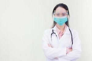 Aziatische vrouwelijke arts in witte laboratoriumjas draagt een medisch gezichtsmasker en gezichtsschild foto