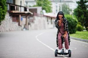 mooie afrikaanse amerikaanse vrouw die segway of hoverboard gebruikt. zwarte meid op zelfbalancerende elektrische scooter met twee wielen. foto