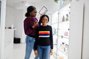 Afro-Amerikaanse vrouw die make-up toepast door visagist bij beauty salon. foto