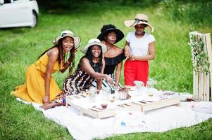 groep afro-amerikaanse meisjes die verjaardagsfeestje vieren en taart buiten snijden met decor. foto