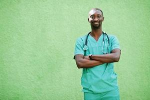 portret van Afrikaanse mannelijke arts met een stethoscoop die een groene jas draagt. foto