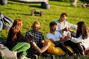 jonge multi-etnische groep mensen kijken naar film op poef in openluchtbioscoop. foto