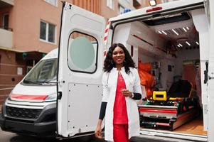 Afro-Amerikaanse vrouwelijke paramedicus staat voor ambulance auto. foto