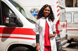 Afro-Amerikaanse vrouwelijke paramedicus staat voor ambulance auto. foto