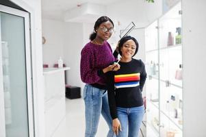 Afro-Amerikaanse vrouw die make-up toepast door visagist bij beauty salon. foto